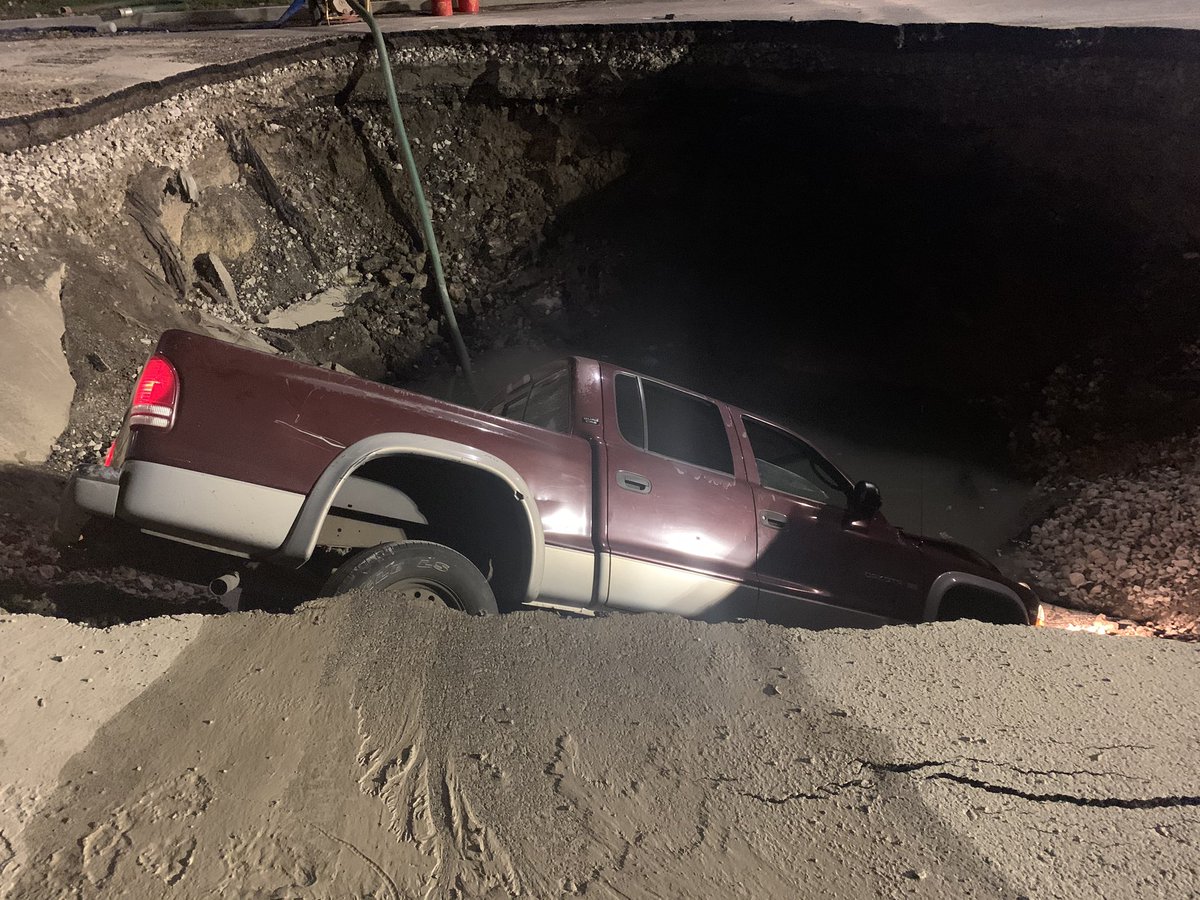 Pick-up truck down in this gaping hole where we saw a water main break yesterday at Lindell and Union. Driver of the truck says he was following someone's directions and ended up down in the he's. He climbed out. He's ok. 